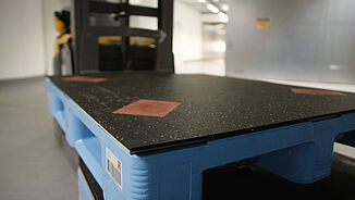 Elektrischer Hubwagen fährt Kunststoffpaletten, die mit REGUPOL auf der Oberseite beklebt sind REGUPOL cargo mat auf Kunststoffpaletten