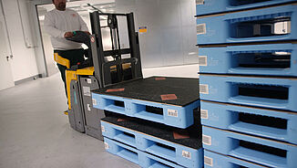 Elektrischer Hubwagen fährt Kunststoffpaletten, die mit REGUPOL auf der Oberseite beklebt sind REGUPOL cargo mat auf Kunststoffpaletten