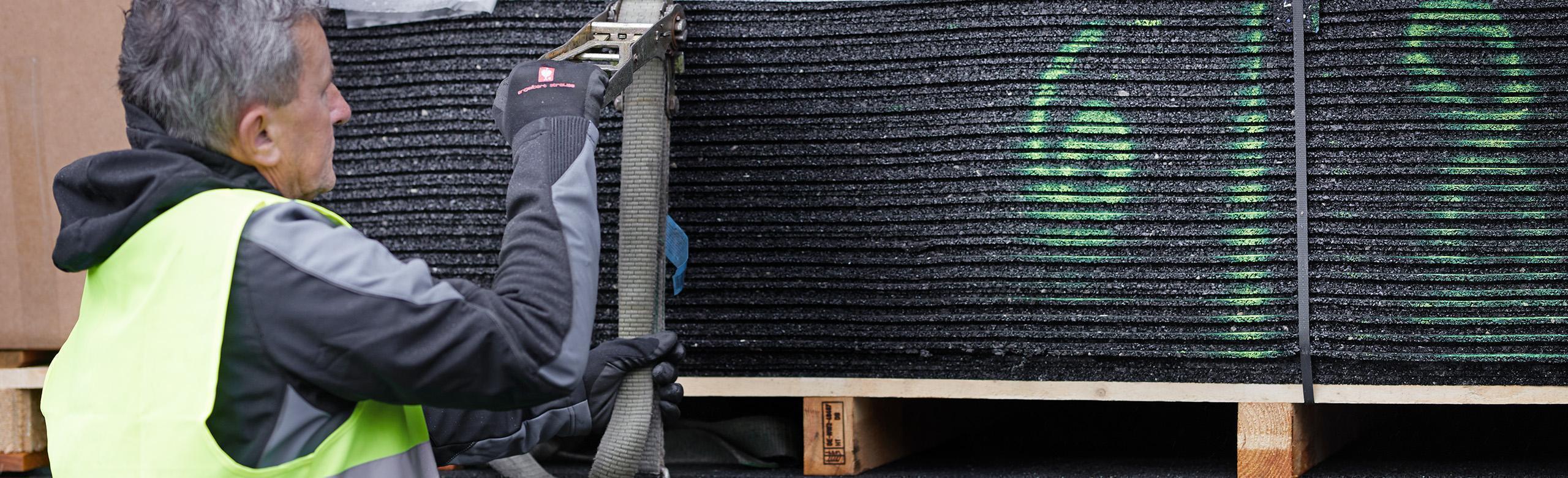 Eine Person befestigt eine Palette, die mit Antirutschmatten beladen ist Antirutschmatten zur Ladungssicherung auf Paletten